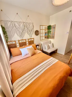 a bedroom with a large bed with an orange blanket at A'more Cosy Stay Near Nuvali at Fullerton Suites in Silang