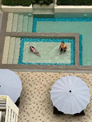 two people swimming in a swimming pool with umbrellas at A'more Cosy Stay Near Nuvali at Fullerton Suites in Silang