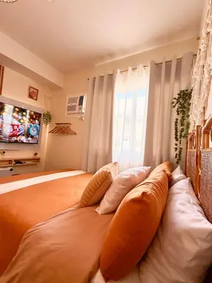 a bedroom with a large bed with pillows and a television at A'more Cosy Stay Near Nuvali at Fullerton Suites in Silang