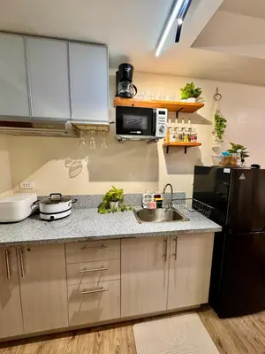 a kitchen with a sink and a black refrigerator at A'more Cosy Stay Near Nuvali at Fullerton Suites in Silang