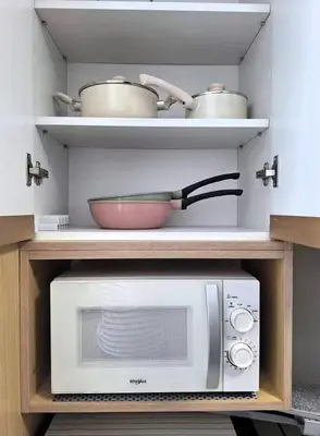 a kitchen with a microwave and pots and pans on shelves at MANILA AIR RESIDENCE 24 floor in Manila