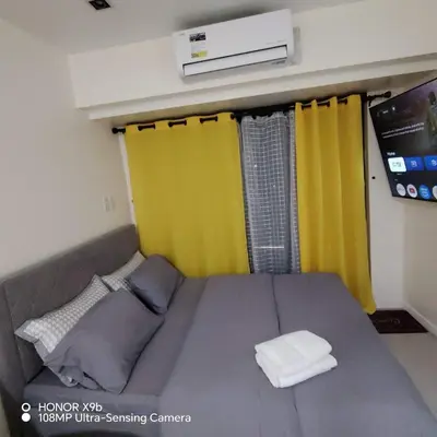 a bed with yellow curtains in a room at Sozy Cozy Knightsbridge Residences 1 in Manila
