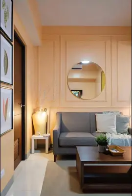 a living room with a blue couch and a mirror at BGC Uptown Condotel in Manila