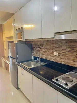 a kitchen with white cabinets and a stainless steel refrigerator at Cozy condo unit in Manila