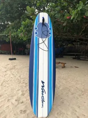 a blue and white surfboard sitting on the beach at Island Garden Beach Resort in Manila