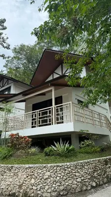 a white house with a white balcony and trees at Island Garden Beach Resort in Manila