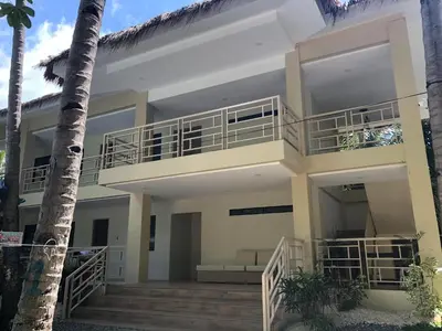 a house with a balcony and a palm tree at Island Garden Beach Resort in Manila