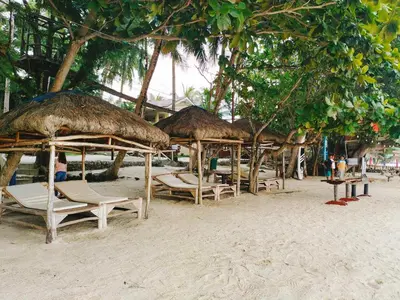 a group of straw umbrellas and chairs on a beach at Island Garden Beach Resort in Manila