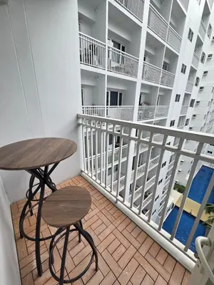 a balcony with a wooden table and stool on it at Royal Suites at Shore Residences near SM MOA and Airport in Manila
