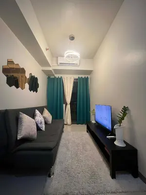 a living room with a black couch and a television at Calm Corner near Mall of Asia in Manila