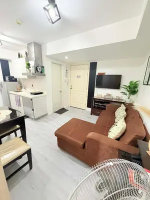 a living room with a brown couch and a kitchen at Azure Destiny's Suites 1214 in Manila