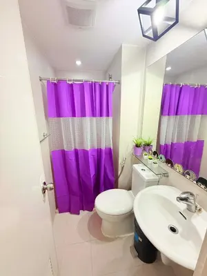 a bathroom with a purple shower curtain and a toilet at Azure Destiny's Suites 1214 in Manila