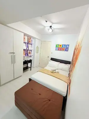 a bedroom with a large bed and a desk at Azure Destiny's Suites 1214 in Manila