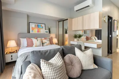 a bedroom with a bed and a couch with pillows at Uptown BGC Condo in Manila