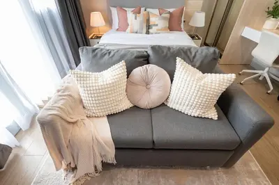 a living room with a couch with pillows and a bed at Uptown BGC Condo in Manila