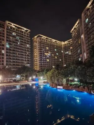 a large pool in front of a large building at night at Azure staycation near Airport beside SM Bicutan in Manila