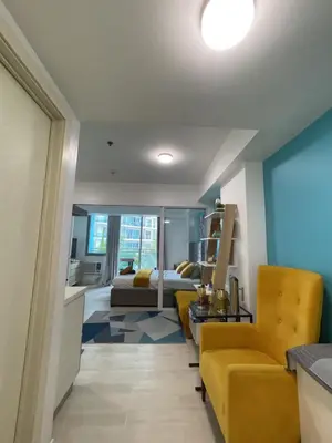 a living room with a yellow couch and a bed at Azure staycation near Airport beside SM Bicutan in Manila