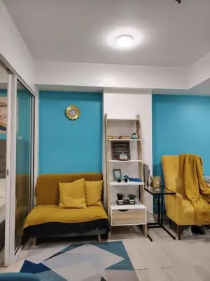 a living room with a yellow couch and blue walls at Azure staycation near Airport beside SM Bicutan in Manila