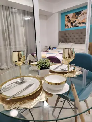 a dining table with plates and wine glasses on it at Azure staycation near Airport beside SM Bicutan in Manila