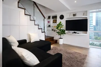 a living room with a black couch and a tv at Stylish Stay in BGC 5th Ave with Free Parking in Manila