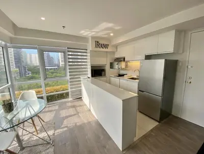 a kitchen with a refrigerator and a table and chairs at Stylish Stay in BGC 5th Ave with Free Parking in Manila