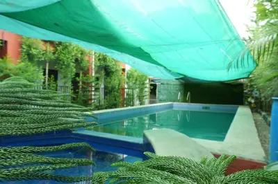 a swimming pool with a blue umbrella and some plants at LAD Private Reosrt in Dasmariñas