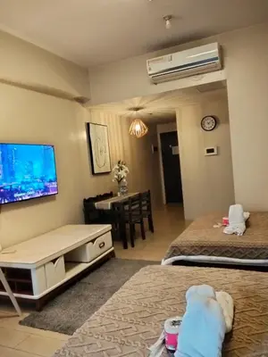 a living room with two beds and a tv on the wall at Cluster4 4A in Manila