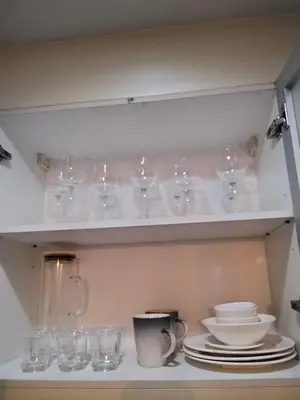 a cupboard with glasses and plates and a coffee mug at Cluster4 4A in Manila
