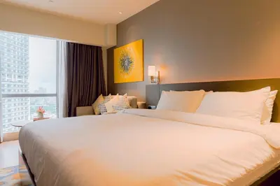 a bedroom with a large white bed and a large window at Primo Espacio at Hotel Residences Acqua in Manila