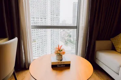 a table with a vase of flowers on it in front of a window at Primo Espacio at Hotel Residences Acqua in Manila