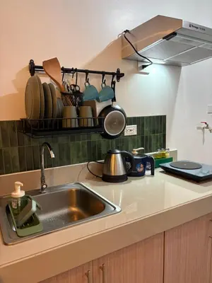 a kitchen sink with pots and pans on a shelf at Katya Suite in Pasong Bayog