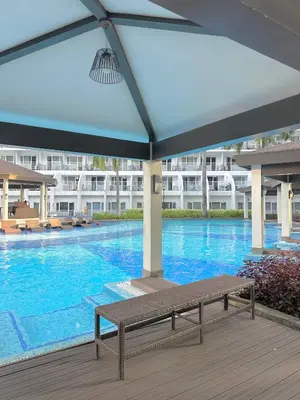 a large swimming pool with a bench in front of a building at Shell Residences MOA by Seph in Manila