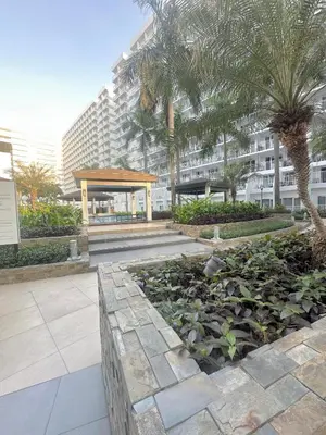 a garden in front of a building with palm trees at Shell Residences MOA by Seph in Manila