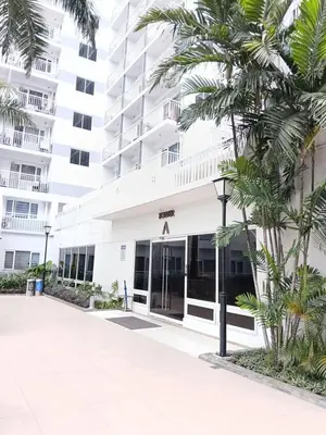 a white building with palm trees in front of it at Shell Residences MOA by Seph in Manila