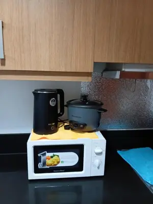 a microwave on a counter with a pot on top at Shell Residences MOA by Seph in Manila