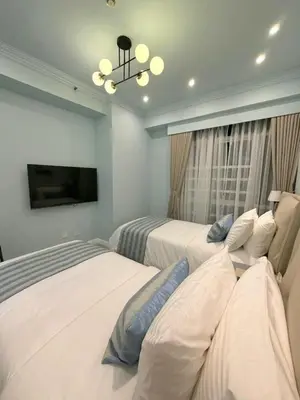 a bedroom with two beds and a chandelier at Modern 4BR in Central BGC Walk to Shangrila and Ascot in Manila