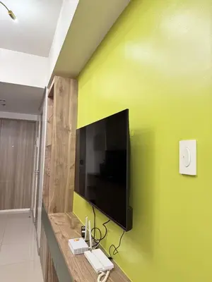 a flat screen tv on a green wall at S residence tower 3 Friendship family hotel in Manila