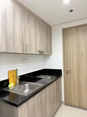 a kitchen with a sink and wooden cabinets at S residence tower 3 Friendship family hotel in Manila