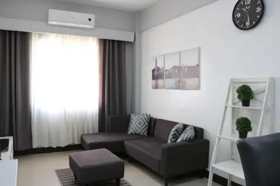 a living room with a couch and a clock on the wall at Sarasota Residential Resort Manila in Manila