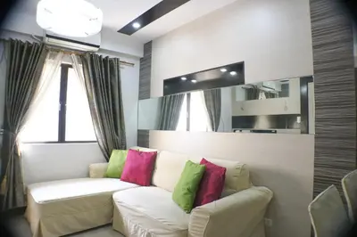 a living room with a white couch with colorful pillows at Sarasota Residential Resort Manila in Manila