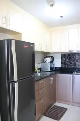 a kitchen with a black refrigerator and wooden cabinets at Sarasota Residential Resort Manila in Manila