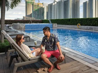 a man and woman sitting in chairs next to a pool at Shangri-La The Fort, Manila in Manila