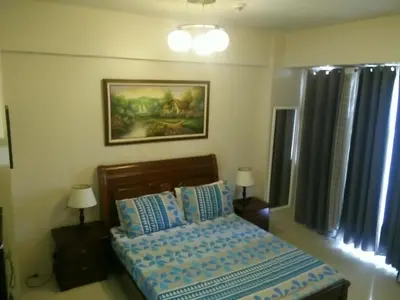 a bedroom with a bed with blue sheets and two lamps at Palm Tree Genlex Condo in Manila