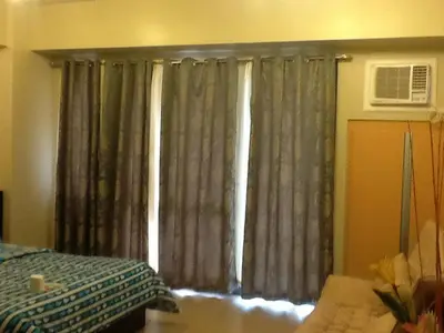a window with curtains in a room with a bed at Palm Tree Genlex Condo in Manila