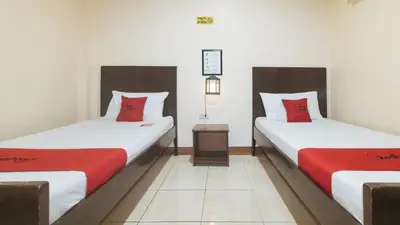 two beds with red pillows in a room at RedDoorz at Elegance Guest House near NAIA T3 in Manila