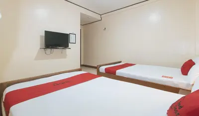 two beds in a room with a tv on the wall at RedDoorz at Elegance Guest House near NAIA T3 in Manila