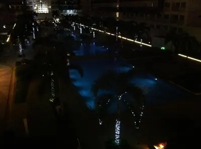 a swimming pool at night with palm trees and lights at Sea Residences - Rheiyn in Manila