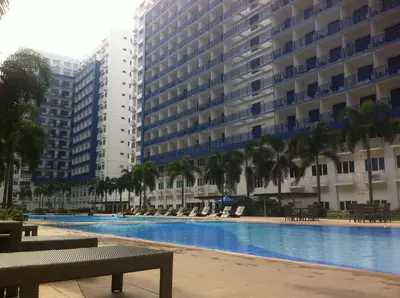 a large swimming pool with palm trees and buildings at Sea Residences - Rheiyn in Manila
