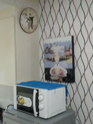 a clock on a wall and a microwave on top of a refrigerator at Sea Residences - Rheiyn in Manila