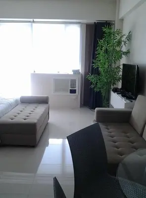 a living room with a couch and a table and a tv at One Palm Tree Villa CC9N in Manila